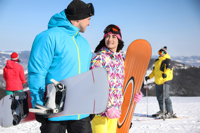 Couple with snowboards at ski resort. Winter vacation