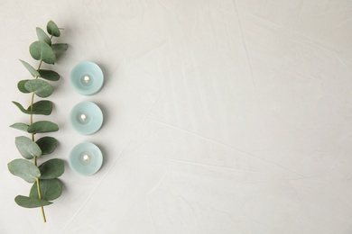 Photo of Burning candles and eucalyptus branch on light background, flat lay. Space for text