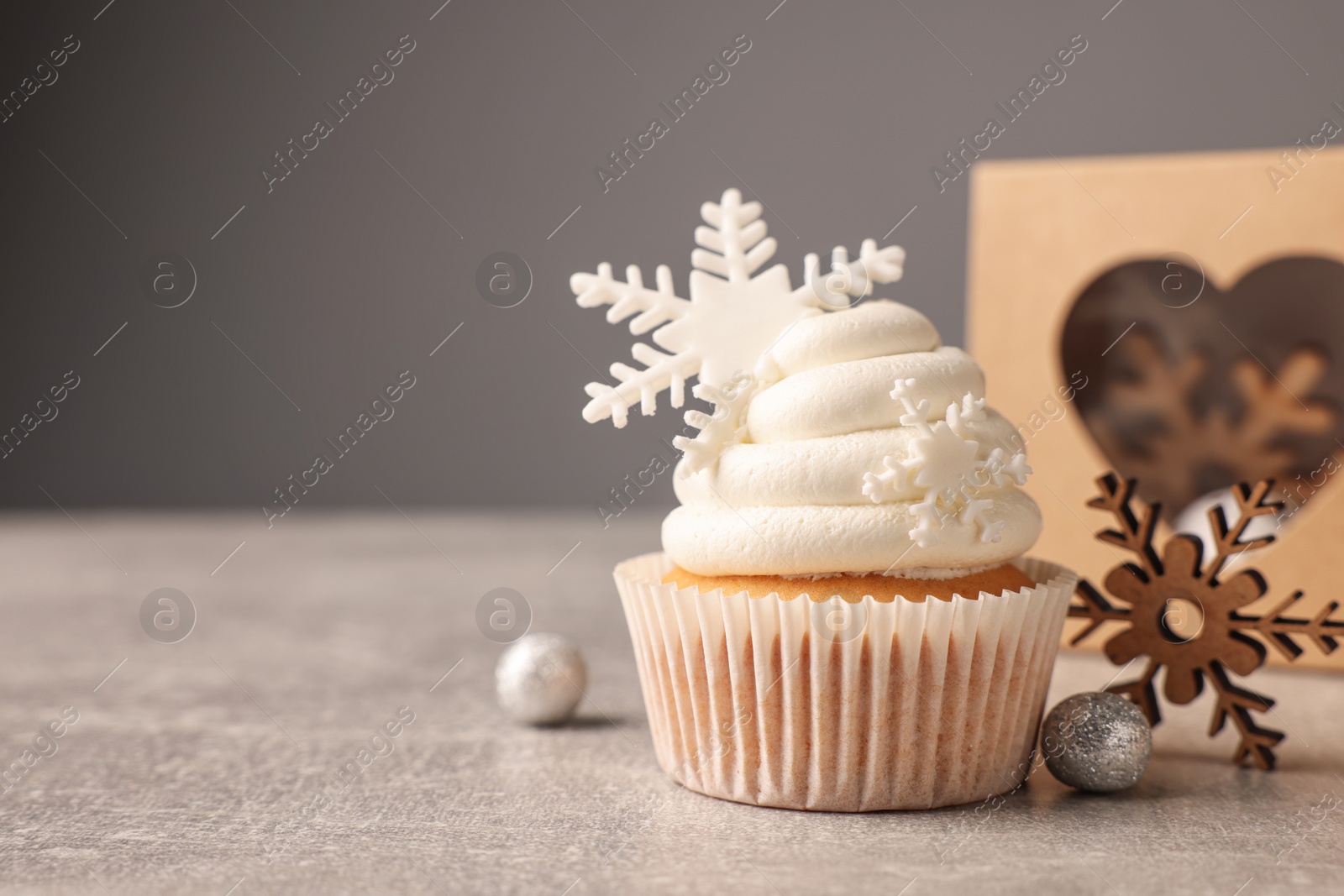 Photo of Tasty Christmas cupcake with snowflakes and festive decor on grey table. Space for text