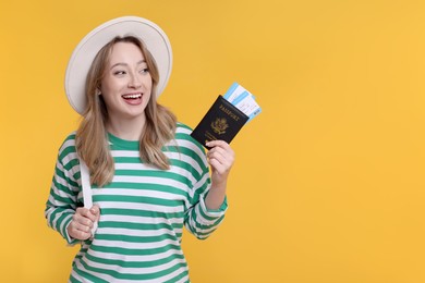Happy young woman with passport, ticket and hat on yellow background, space for text