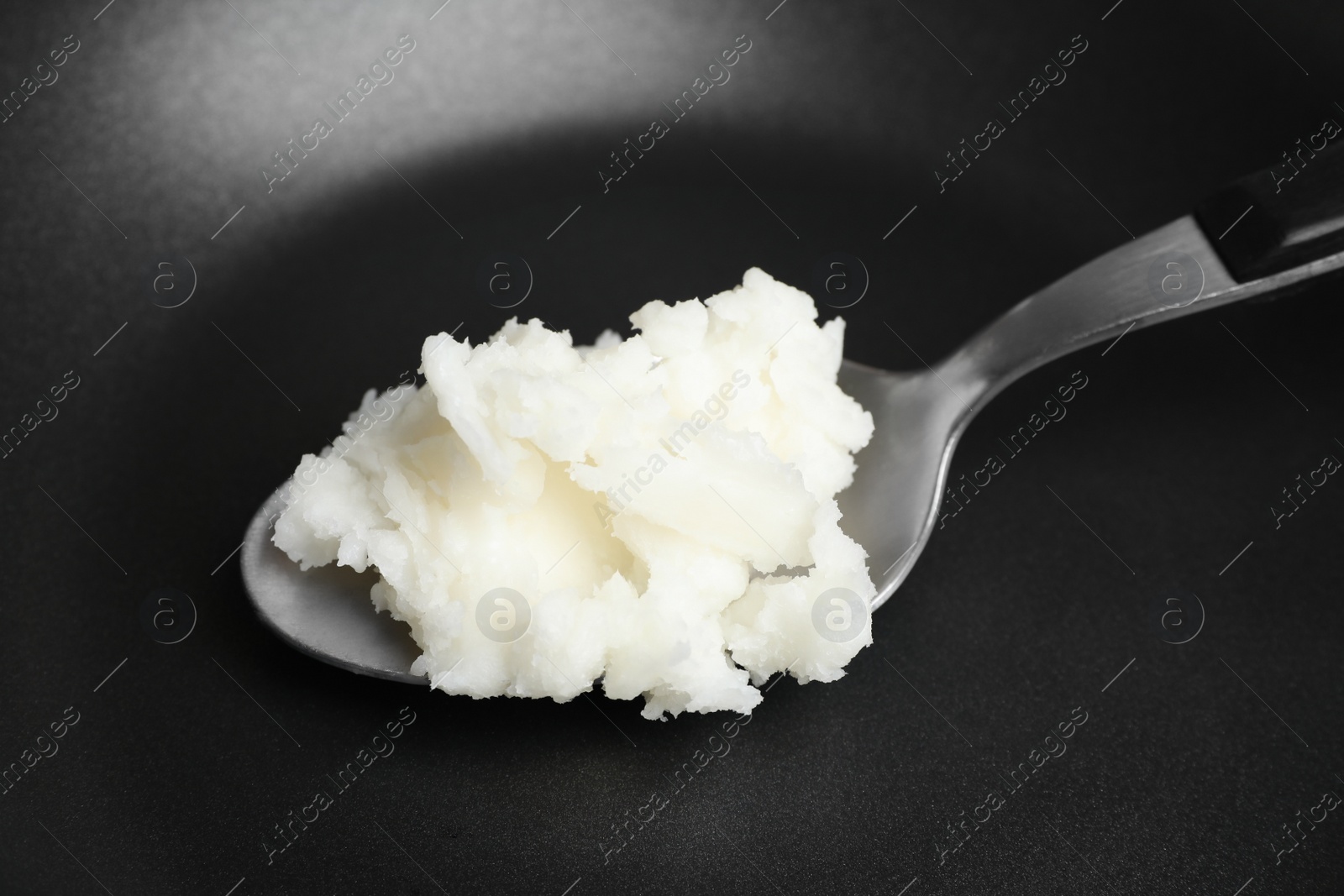 Photo of Frying pan with coconut oil and spoon, closeup