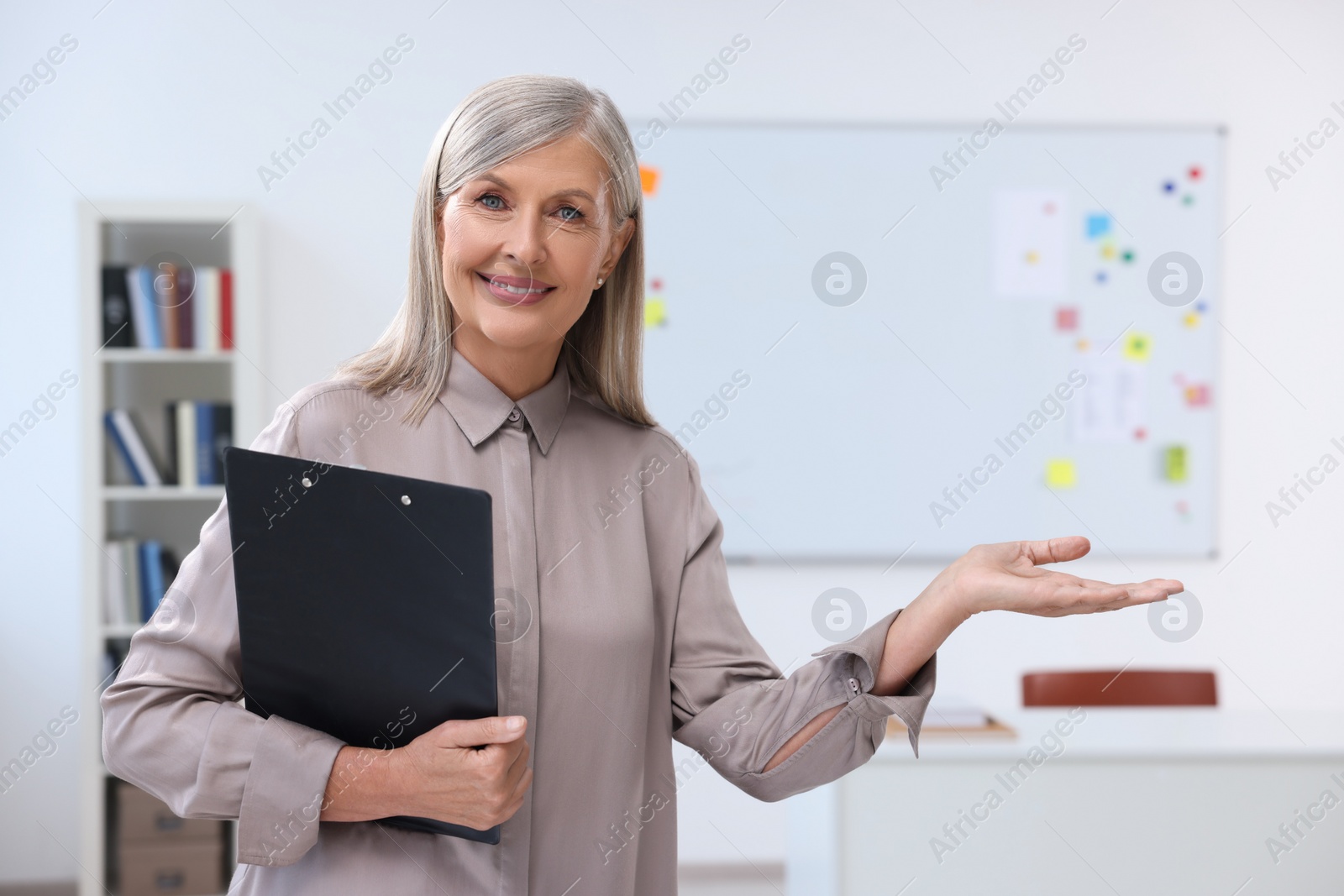 Photo of Portrait of professor with clipboard in classroom, space for text