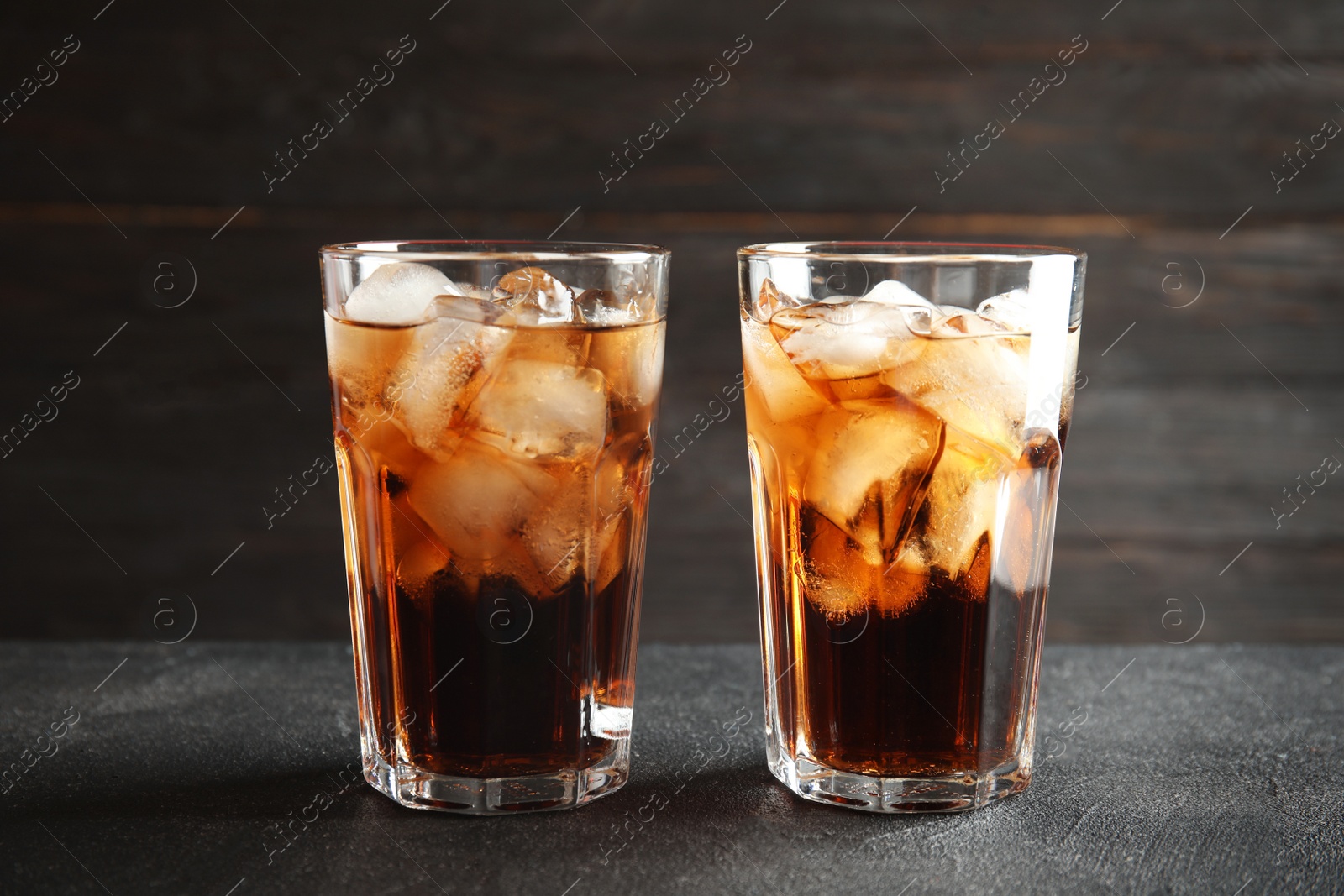 Photo of Glasses of refreshing cola with ice cubes on table
