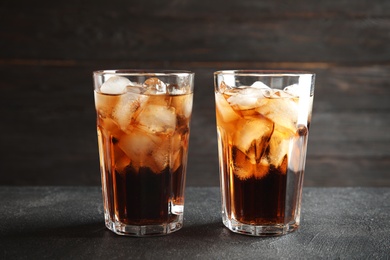 Glasses of refreshing cola with ice cubes on table