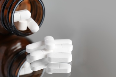 Photo of Bottle with pills on reflective surface