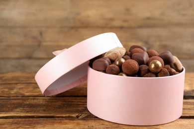 Different delicious chocolate candies in box on wooden table