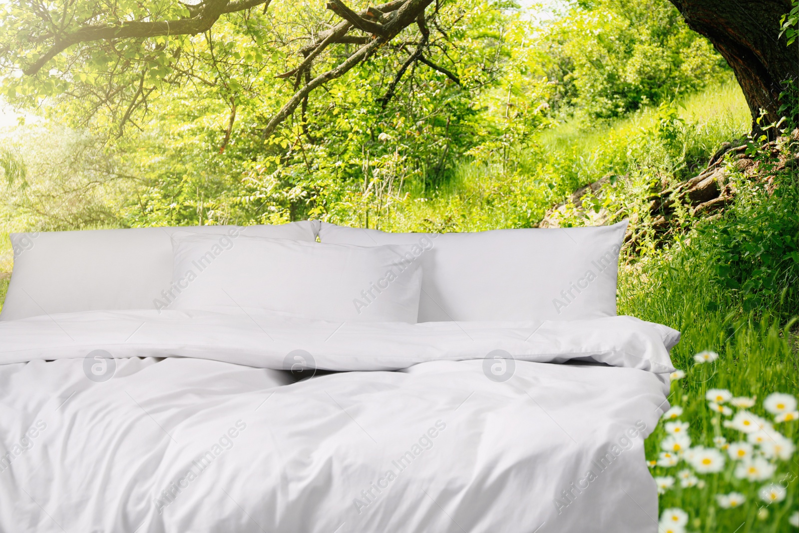 Image of Comfortable bed with soft pillows outdoors on sunny day