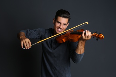 Happy man playing violin on black background