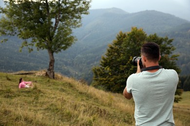 Professional photographer taking picture of woman in mountains, back view