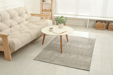Photo of Stylish rug with pattern and table on floor in living room