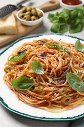 Photo of Delicious pasta with anchovies, olives and basil on white table