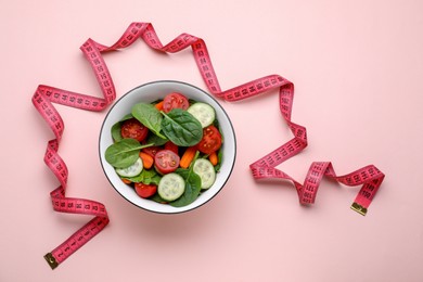 Photo of Measuring tape and salad on pink background, flat lay