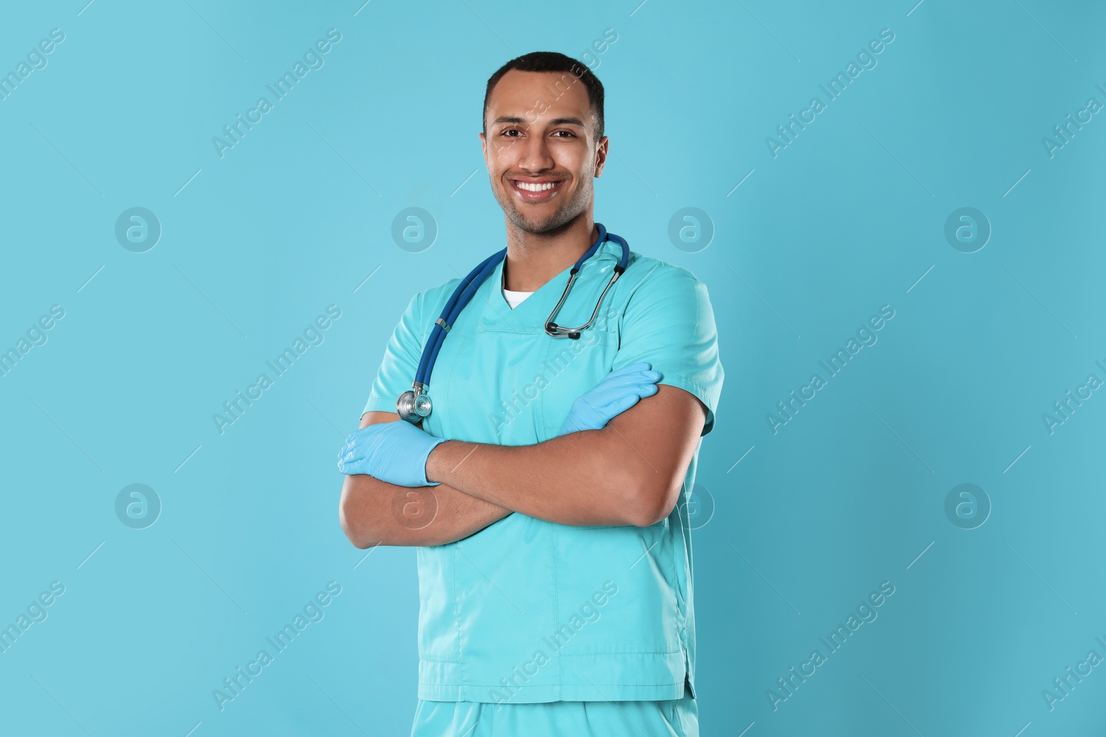 Photo of Happy doctor or medical assistant (male nurse) with stethoscope on turquoise background