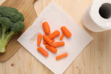 Photo of Carrots drying on paper towel and broccoli on wooden table, flat lay