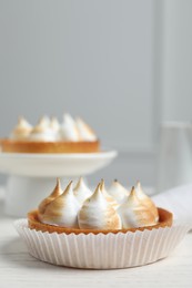 Tartlet with meringue on white table, closeup and space for text. Delicious dessert