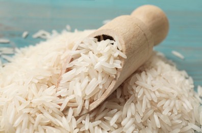 Photo of Raw basmati rice and wooden scoop on table, closeup