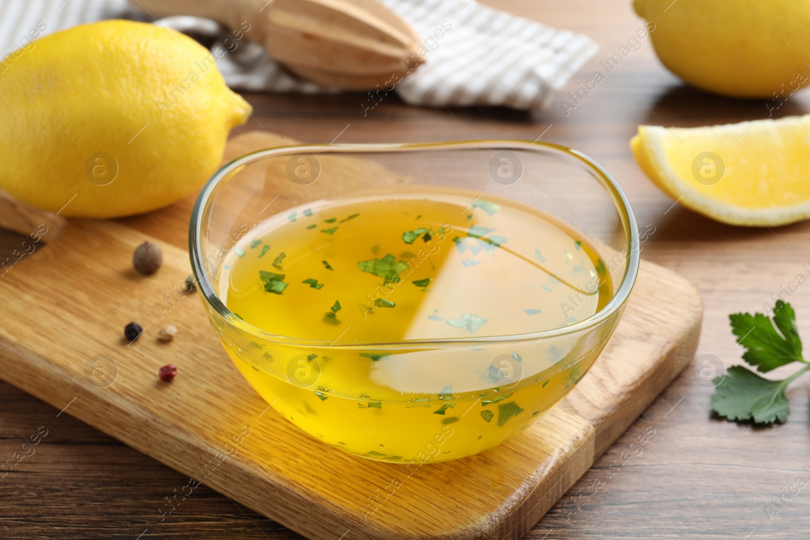 Photo of Bowl with lemon sauce and ingredients on wooden table. Delicious salad dressing