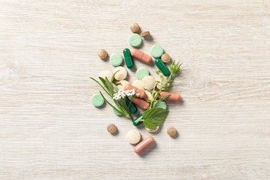 Photo of Different pills and herbs on wooden table, flat lay. Dietary supplements