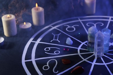 Natural stones for zodiac signs, drawn astrology chart and burning candles on black table. Color tone effect