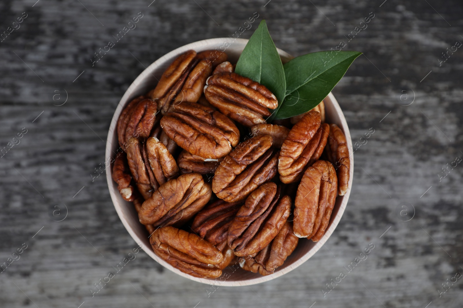 Photo of Tasty pecan nuts on grey wooden table, top view