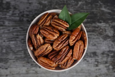 Tasty pecan nuts on grey wooden table, top view