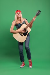 Photo of Happy hippie woman playing guitar on green background
