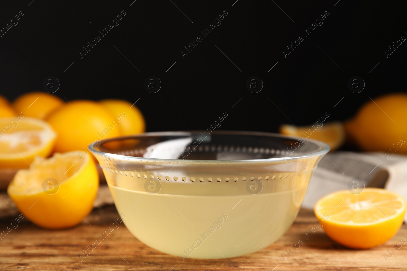 Photo of Freshly squeezed lemon juice in glass bowl on wooden table