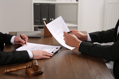 Photo of Law and justice. Lawyers working with documents at wooden table in office, closeup