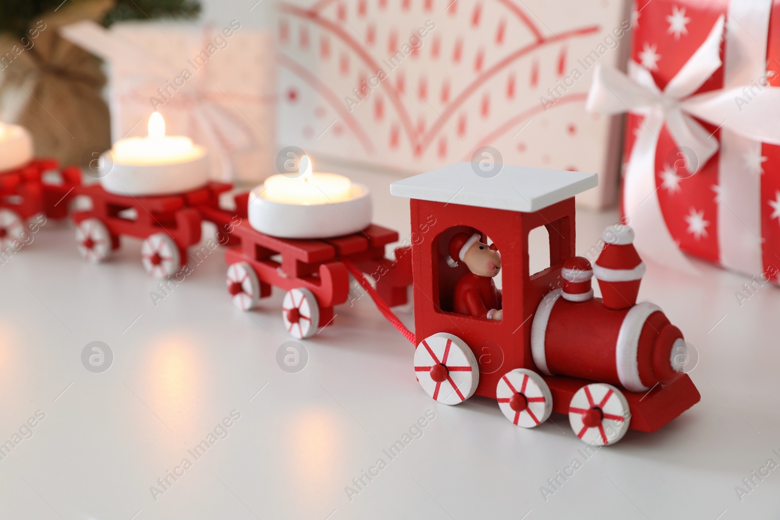 Photo of Red toy train as Christmas candle holder on white table, closeup