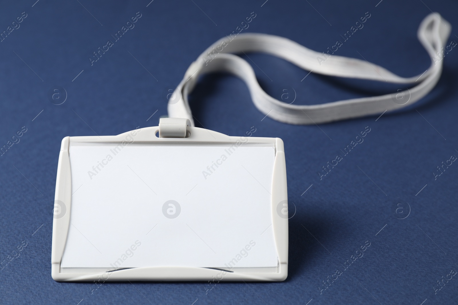 Photo of Blank badge with string on blue background, closeup