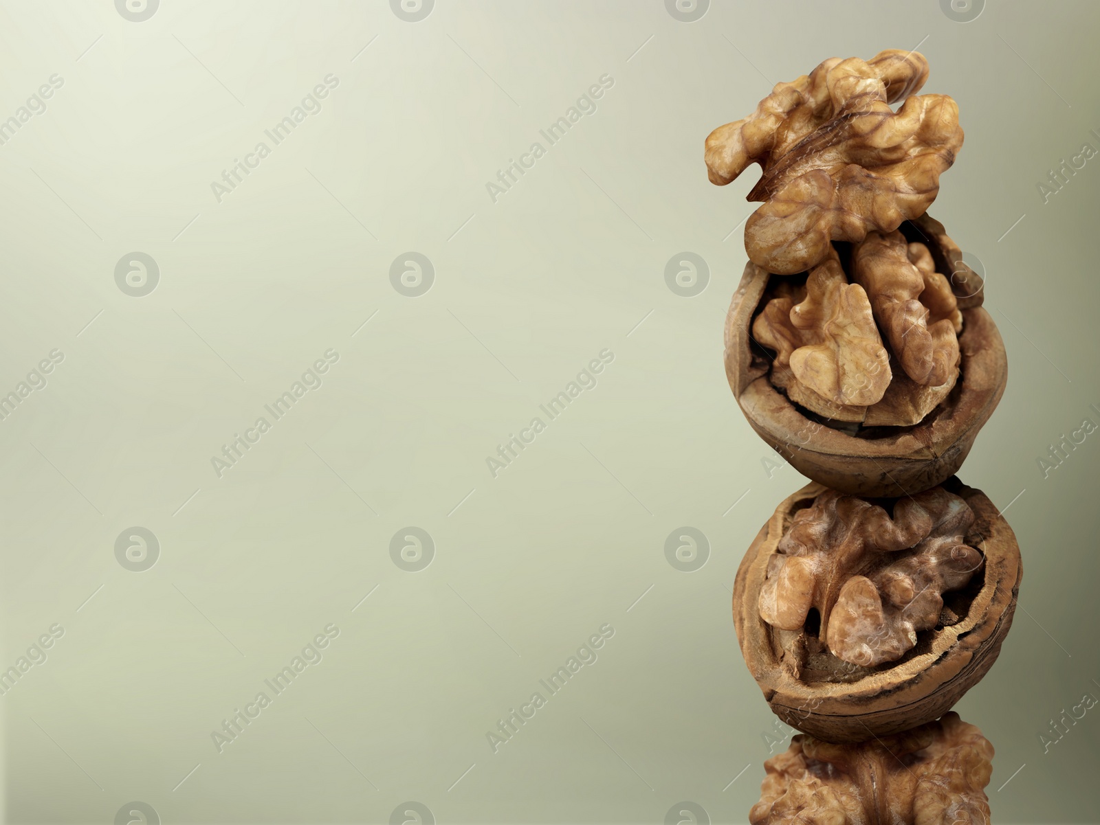 Image of Stacked walnuts on light grey gradient background, space for text