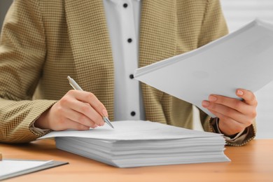 Photo of Woman signing documents at table in office, closeup