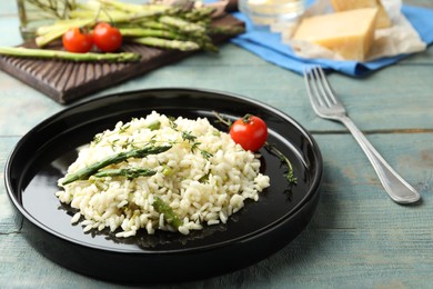 Photo of Delicious risotto with asparagus served on blue wooden table