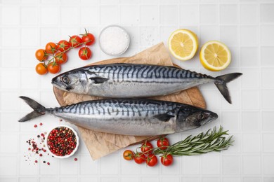 Raw mackerel, tomatoes and rosemary on white tiled table, flat lay
