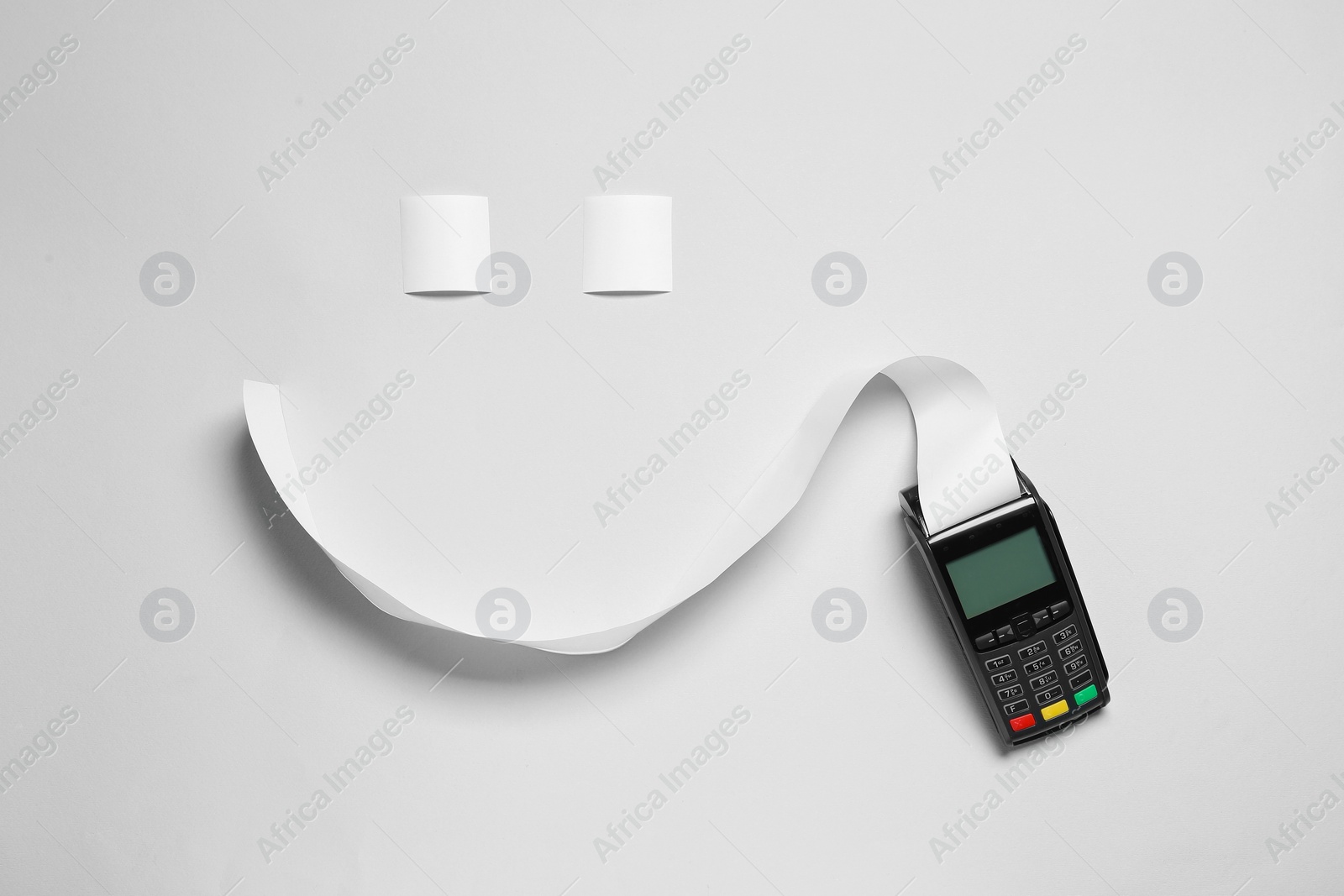 Photo of Payment terminal and smiley face made of thermal paper for receipt on light grey background, flat lay