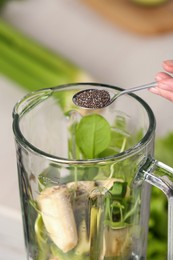 Photo of Woman adding chia seeds into blender with ingredients for green smoothie, closeup