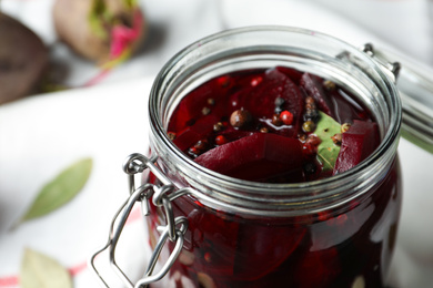 Photo of Pickled beets in glass preserving jar on table, closeup