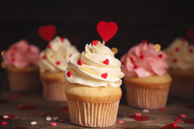 Photo of Tasty sweet cupcakes on wooden table. Happy Valentine's Day