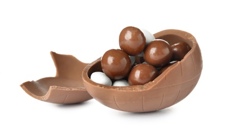 Broken chocolate egg with candies on white background