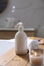 Photo of Wooden bath tray with shower gel, candle and fresh towel on tub indoors