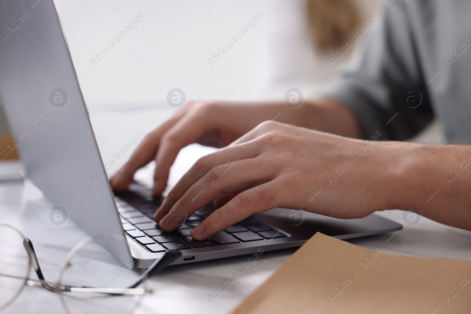 Photo of Man working on laptop at white desk indoors, closeup
