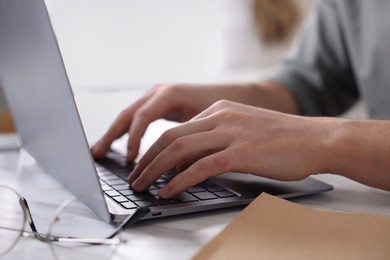 Photo of Man working on laptop at white desk indoors, closeup