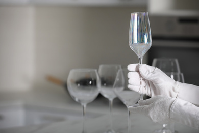 Photo of Person in white gloves checking cleanliness of glass indoors, closeup. Space for text
