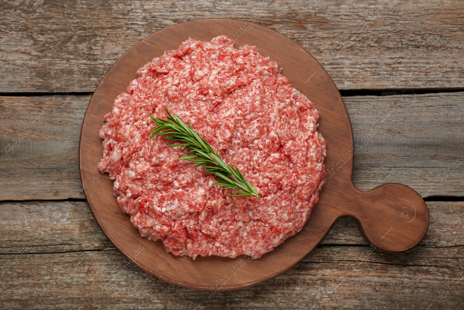 Photo of Raw fresh minced meat with rosemary on wooden table, top view