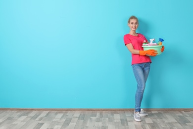 Photo of Woman with cleaning supplies near color wall