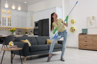 Spring cleaning. Young woman with mop singing while tidying up at home