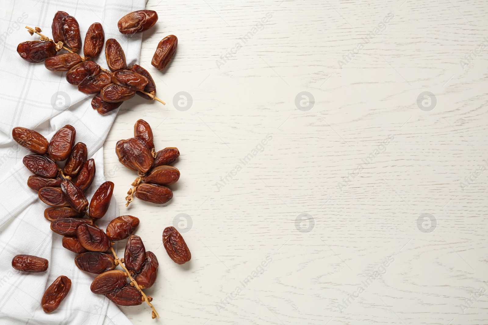 Photo of Branches of tasty sweet dried dates on white wooden table, flat lay. Space for text