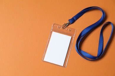 Photo of Blank badge with string on orange background, top view. Space for text