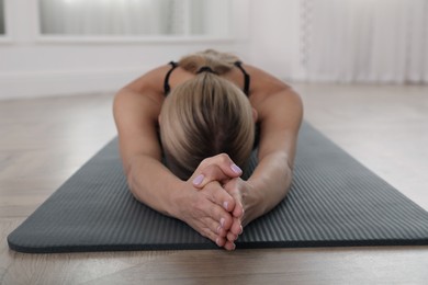 Photo of Woman practicing yoga indoors, focus on hands