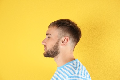 Young man on color background. Hearing problem